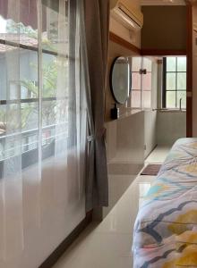 Dormitorio con ventana con espejo y cama en Hidden Hill Villa Kota Bunga by Citrus House, en Cipanas