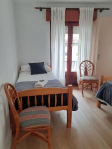 1 dormitorio con 1 cama con silla y ventana en Pensión Río Umia, en Caldas de Reis