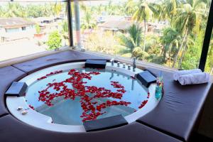 a table with red flowers in a room with a window at Sia Signature Calangute in Calangute