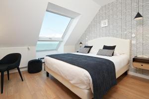 a bedroom with a large bed and a large window at Les Chants d'Ailes - Hôtel Face Mer in La Turballe