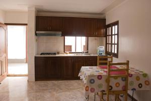una cocina con armarios de madera y una mesa con sillas. en Self-catering Apartment w/ Terrace, en Tarrafal