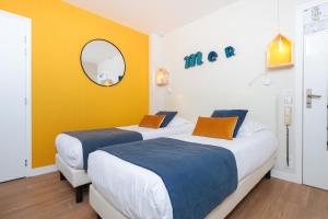 ラ・テュルバルにあるLes Chants d'Ailes - Hôtel Face Merの黄色い壁の客室で、ベッド2台、鏡が備わります。