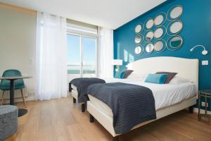 two beds in a bedroom with a blue wall at Les Chants d'Ailes - Hôtel Face Mer in La Turballe