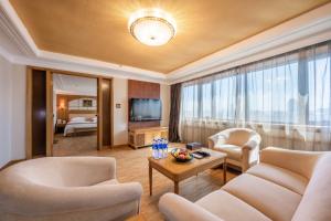 a living room with a couch and chairs and a television at Hotel Silverland in Dongguan