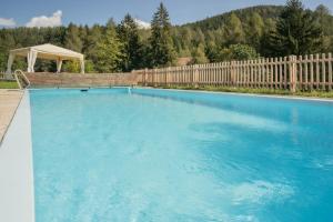 a large blue swimming pool with a wooden fence and a gazebo at Hotel Langeshof in Anterivo