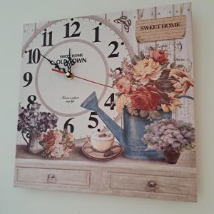 a clock sitting on top of a dresser with flowers at Sweet home in Šiauliai