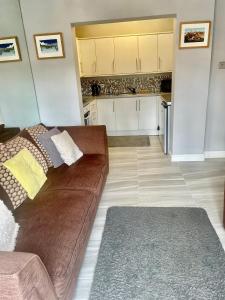 a living room with a brown couch and a kitchen at Gillygate Holiday Apartment in York