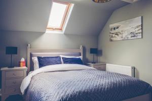 a bedroom with a bed with blue sheets and a window at Maytown Cottage in Rosslare