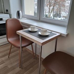a table with two cups and two chairs in a kitchen at Sweet home in Šiauliai