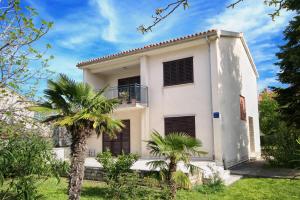 a white house with palm trees in front of it at Merlini in Medulin