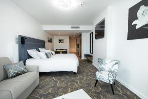 une chambre d'hôtel avec un lit et un canapé dans l'établissement Le Barracuda & Spa, Centre Port, pieds dans l'eau, vue mer, à Brest