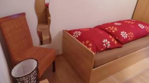 LallingにあるFerienwohnung Zur schönen Aussichtの赤い枕と椅子付きのベッドが備わる小さな客室です。