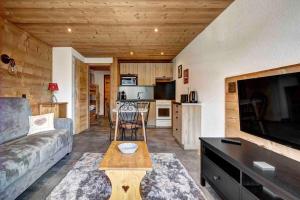 a living room with a couch and a tv and a kitchen at Beauregard 2 in Le Grand-Bornand