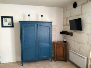 Cette chambre comprend une armoire bleue et une télévision. dans l'établissement Le Gîte des Marguerites, à Montrichard