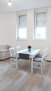 einen weißen Tisch und Stühle in einem Zimmer mit zwei Fenstern in der Unterkunft Hercegovina Rent in Ljubuški