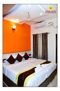 1 dormitorio con 1 cama grande y pared de color naranja en Hotel Omicron 1 BHK Studio room en Bangalore
