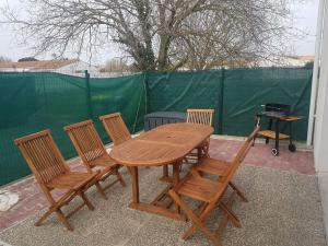 una mesa de madera, 4 sillas y una parrilla en Maison au calme 2 à 300 m de la plage 2 chambres en La Cotinière
