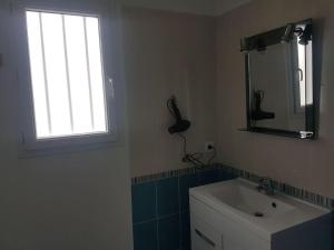 La salle de bains est pourvue d'un lavabo, d'une fenêtre et d'un miroir. dans l'établissement Maison au calme 2 à 300 m de la plage 2 chambres, à La Cotinière