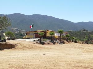 a building with a flag on top of a dirt field at El Rincón Del Valle en la Ruta Del Vino in Valle de Guadalupe