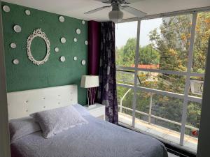 um quarto com uma parede verde, uma cama e uma janela em Satya Suites & Portal San Angel Flats em Cidade do México