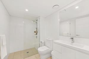 a white bathroom with a toilet and a sink at The Shoal in Shoal Bay