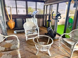 a screened in porch with chairs and a treadmill at Swan Valley Residence in Baie du Tombeau
