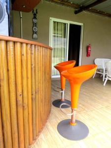 zwei orangefarbene Stühle auf einem Holzboden neben einem Zaun in der Unterkunft Swan Valley Residence in Baie du Tombeau