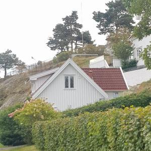 una casa blanca con techo rojo en una colina en Lys og lettstelt leilighet med utsikt over byen, en Sandefjord
