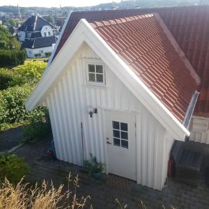 un pequeño cobertizo blanco con techo rojo en Lys og lettstelt leilighet med utsikt over byen, en Sandefjord