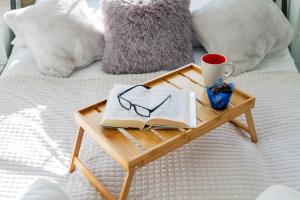 a tray with a book and glasses on a bed at Przymorze Falowiec Apartment by Renters in Gdańsk