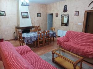 sala de estar con sofás rojos, mesa y chimenea en Casas Rurales Ivan El Penas en Benizar