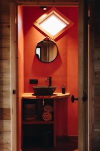 baño con pared roja con lavabo y espejo en Les cabanes des Pierreux en Gesves