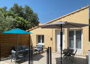 d'une terrasse avec des tables, des chaises et un parasol. dans l'établissement Séjour détente et bien être avec SPA au gîte l Olipin, à Aubais