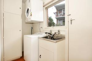 uma pequena cozinha branca com um lavatório e uma janela em Lisson Holiday Rental em Melbourne