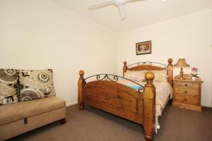 ein Schlafzimmer mit einem Holzbett und einem Sofa in der Unterkunft Lisson Holiday Rental in Melbourne