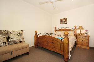 a bedroom with a wooden bed and a couch at Lisson Holiday Rental in Melbourne