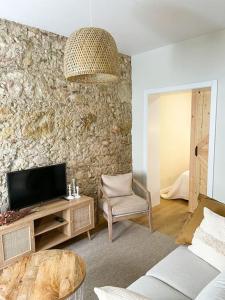 sala de estar con TV y pared de piedra. en Olivete Apartment en Lisboa