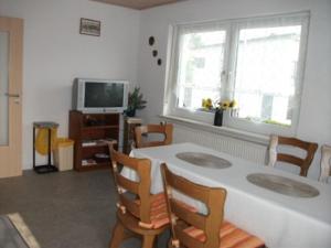 ein Wohnzimmer mit einem Tisch, Stühlen und einem TV in der Unterkunft Ferienwohnung Fischer mit Balkon in Hambach
