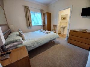 a bedroom with a bed and a dresser and a television at Solway Retreat in Gretna