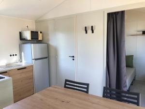 uma pequena cozinha com uma mesa e um frigorífico em Mobile-home Pin em Bec-de-Mortagne