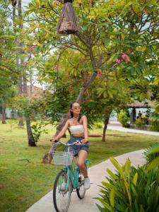a woman is riding a bike down a sidewalk at Gili Air Lagoon Resort By Waringin Hospitality in Gili Islands