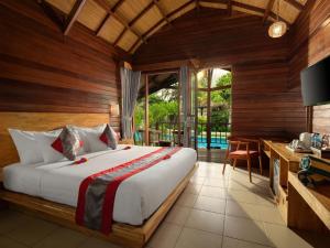 - une chambre avec un grand lit et un bureau dans l'établissement Gili Air Lagoon Resort By Waringin Hospitality, à Gili Air