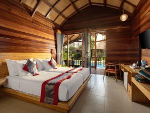 una camera da letto con un letto grande in una stanza con pareti in legno di Gili Air Lagoon Resort By Waringin Hospitality a Gili Air