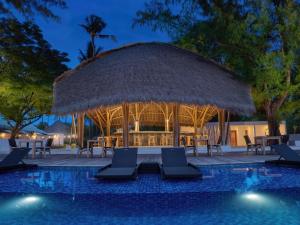 a resort with a pool with chairs and a gazebo at Gili Air Lagoon Resort By Waringin Hospitality in Gili Islands