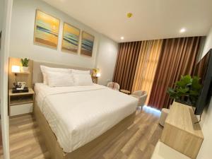sypialnia z białym łóżkiem i telewizorem w obiekcie Vu Gia Hotel Phu Quoc w Duong Dong