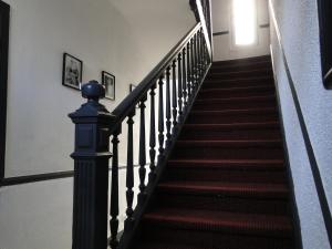 un escalier dans une maison dotée de moquette rouge et d'une porte dans l'établissement Tout confort et proximité., à Vichy