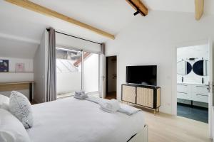 a white bedroom with a large bed and a tv at Pick A Flat's Apartment in La Chapelle - Impasse du Curé in Paris
