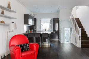 a red chair in a living room with a kitchen at Stunning flat in Notting Hill with roof top in London
