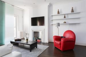 a living room with a red chair and a coffee table at Stunning flat in Notting Hill with roof top in London