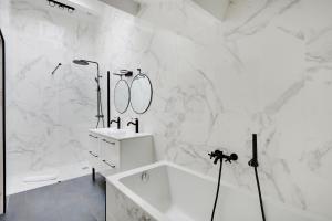 biała łazienka z wanną i umywalką w obiekcie Pick A Flat's Apartment in La Chapelle - Impasse du Curé w Paryżu +11 zdjęć